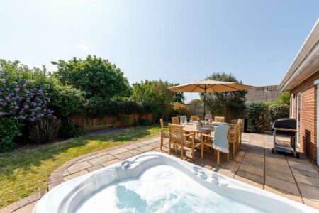 Outdoor patio area with a hot tub and dining set, ideal for group accommodation in East Wittering.