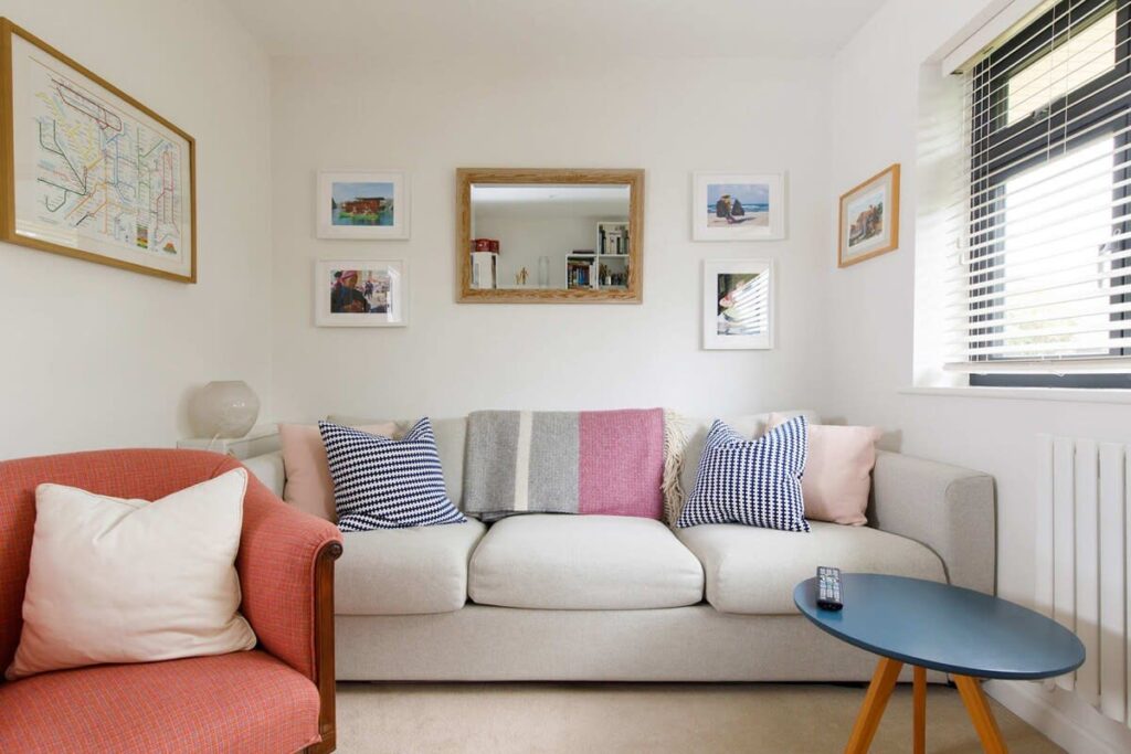 Cosy living room in a coastal accommodation in Bosham, featuring a sofa, armchair, and coffee table with cushions and throw pillows